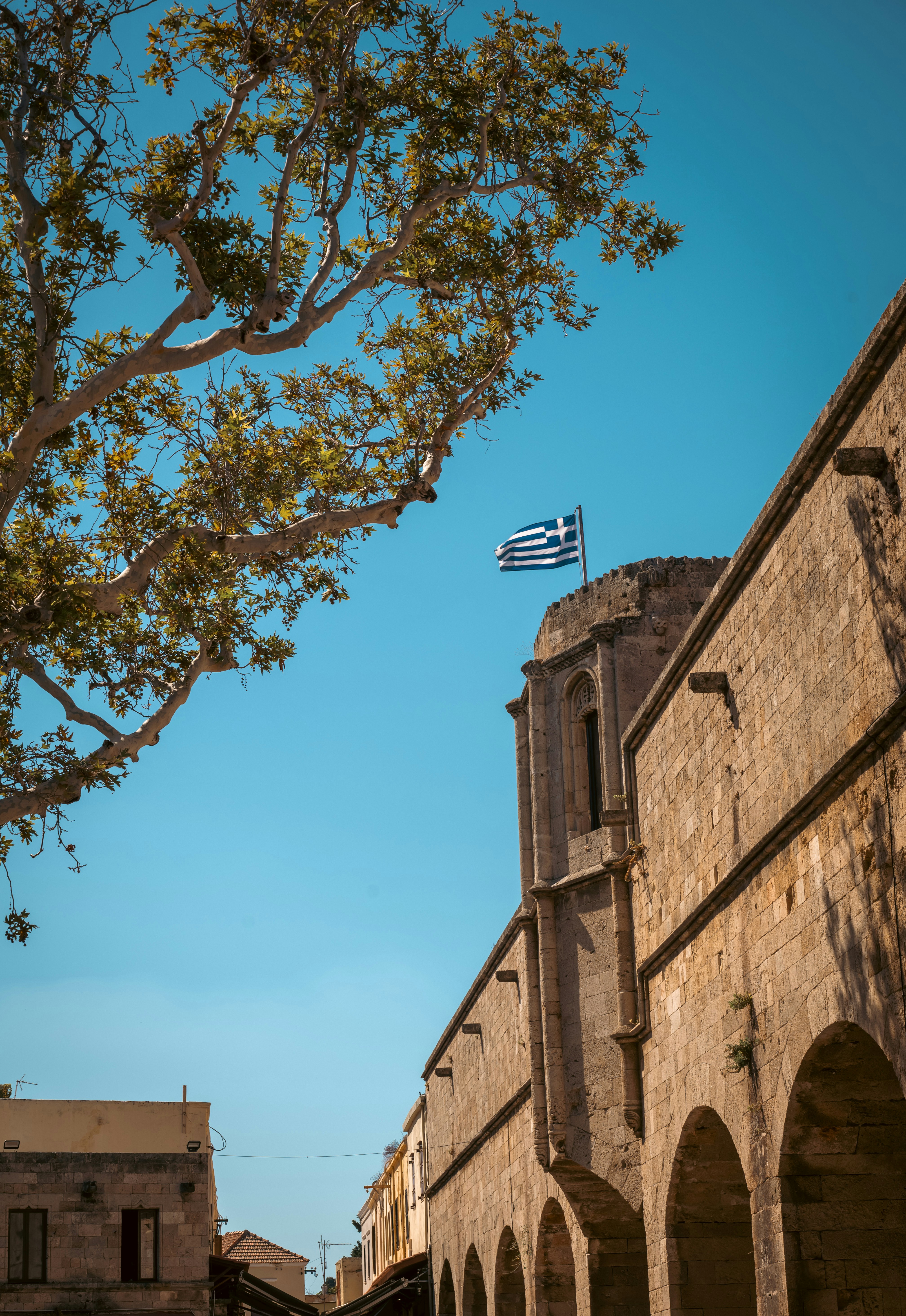 Greek flag flies above ancient stone building