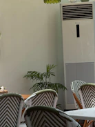 Chairs and tall air conditioner in a room.