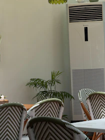 Chairs and tall air conditioner in a room.