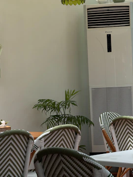 Chairs and tall air conditioner in a room.