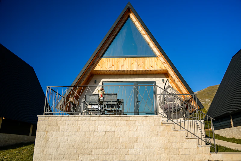 Finished stone-and-timber mountain modern home on the same lot, framed by the pine ridge