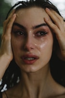 A woman crying with hands on her head.