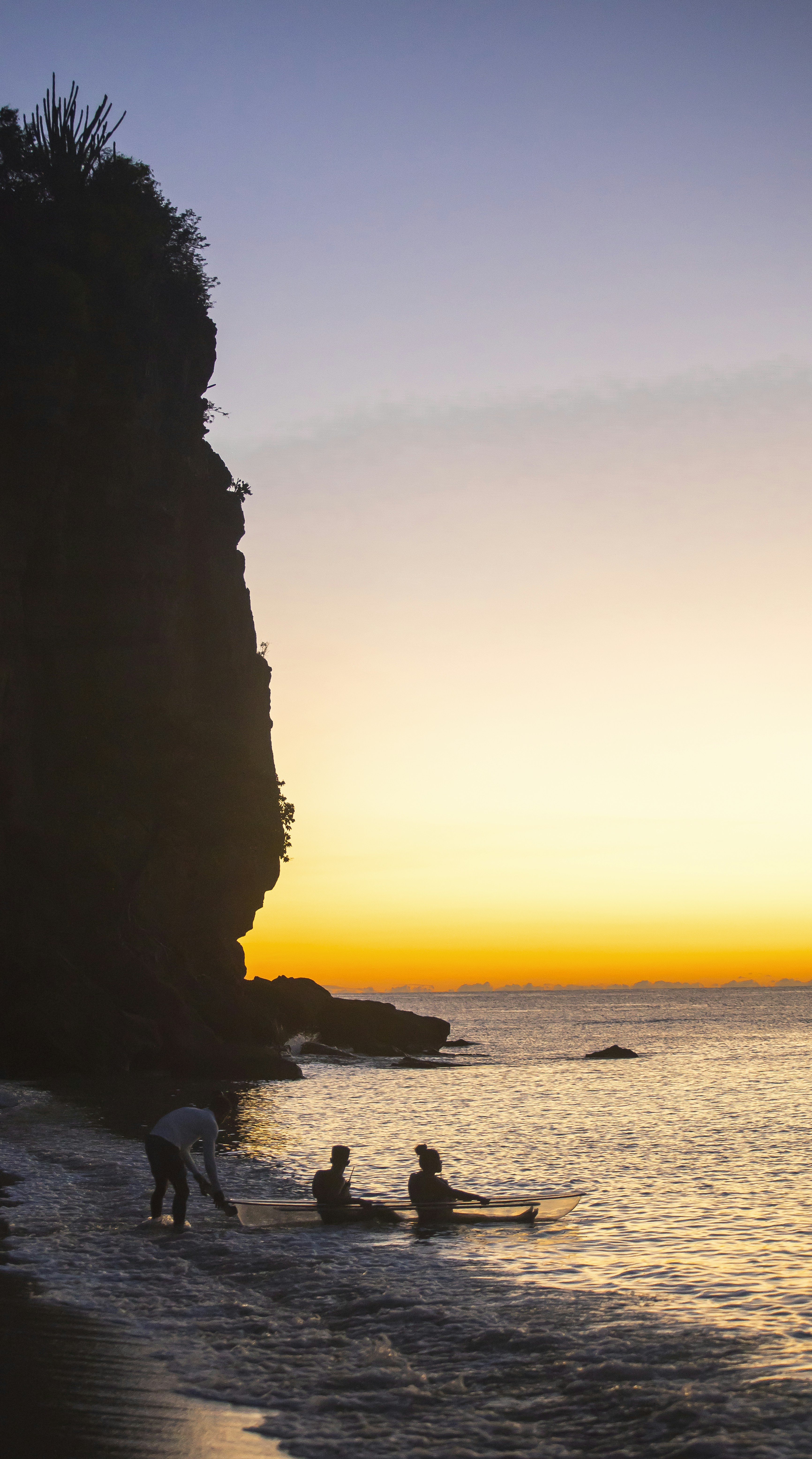 Paddleboarders near cliff at sunset