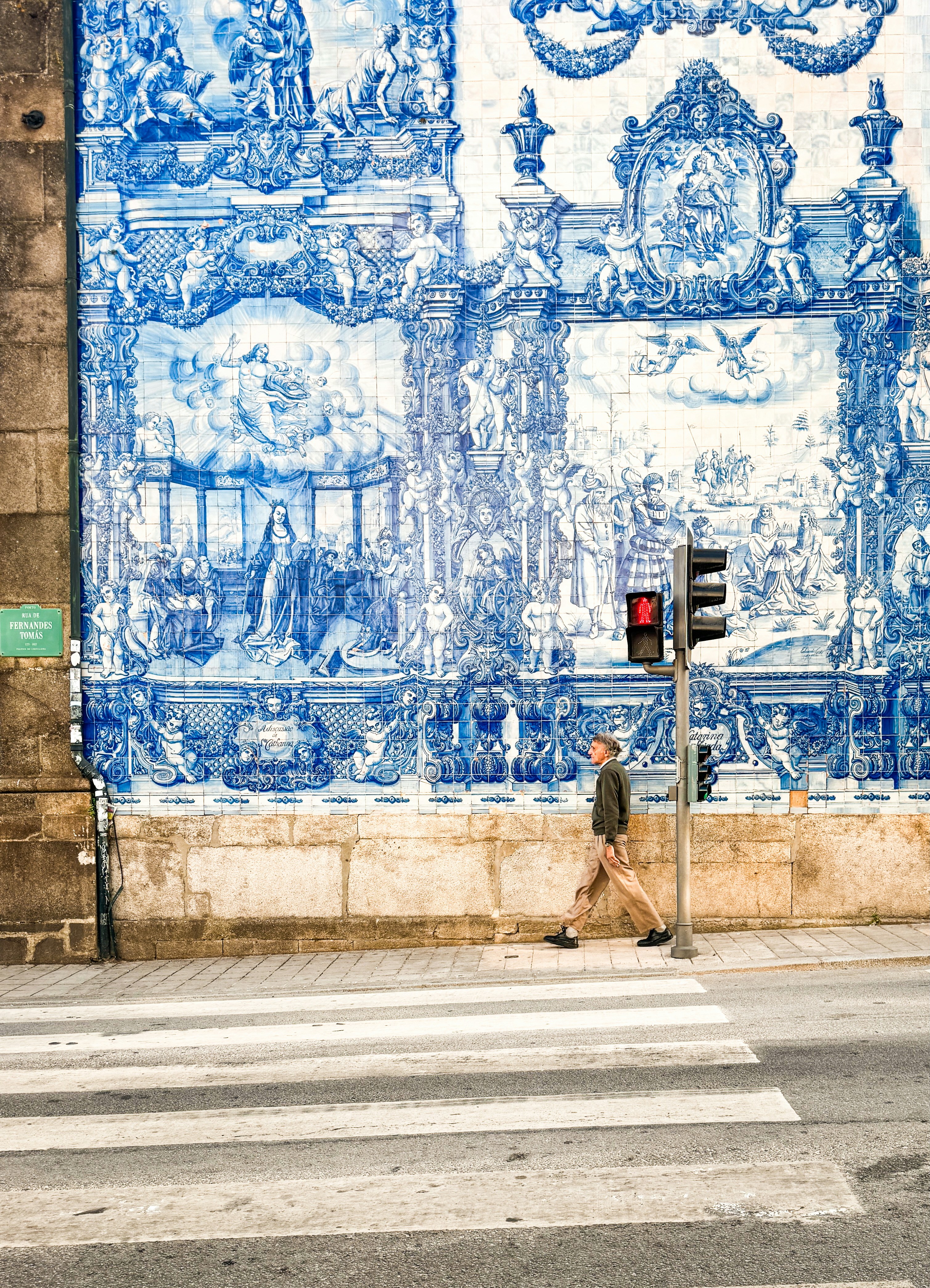 Hombre cruza la calle por una pared de azulejos