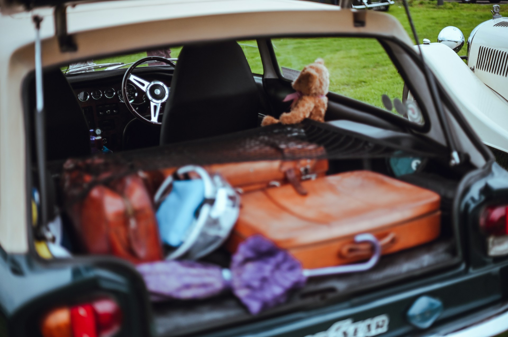 Open car trunk filled with luggage and teddy bear.