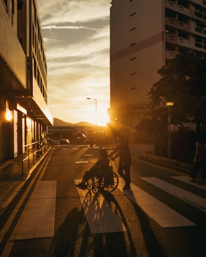 Sunset illuminates people crossing a street in a city.