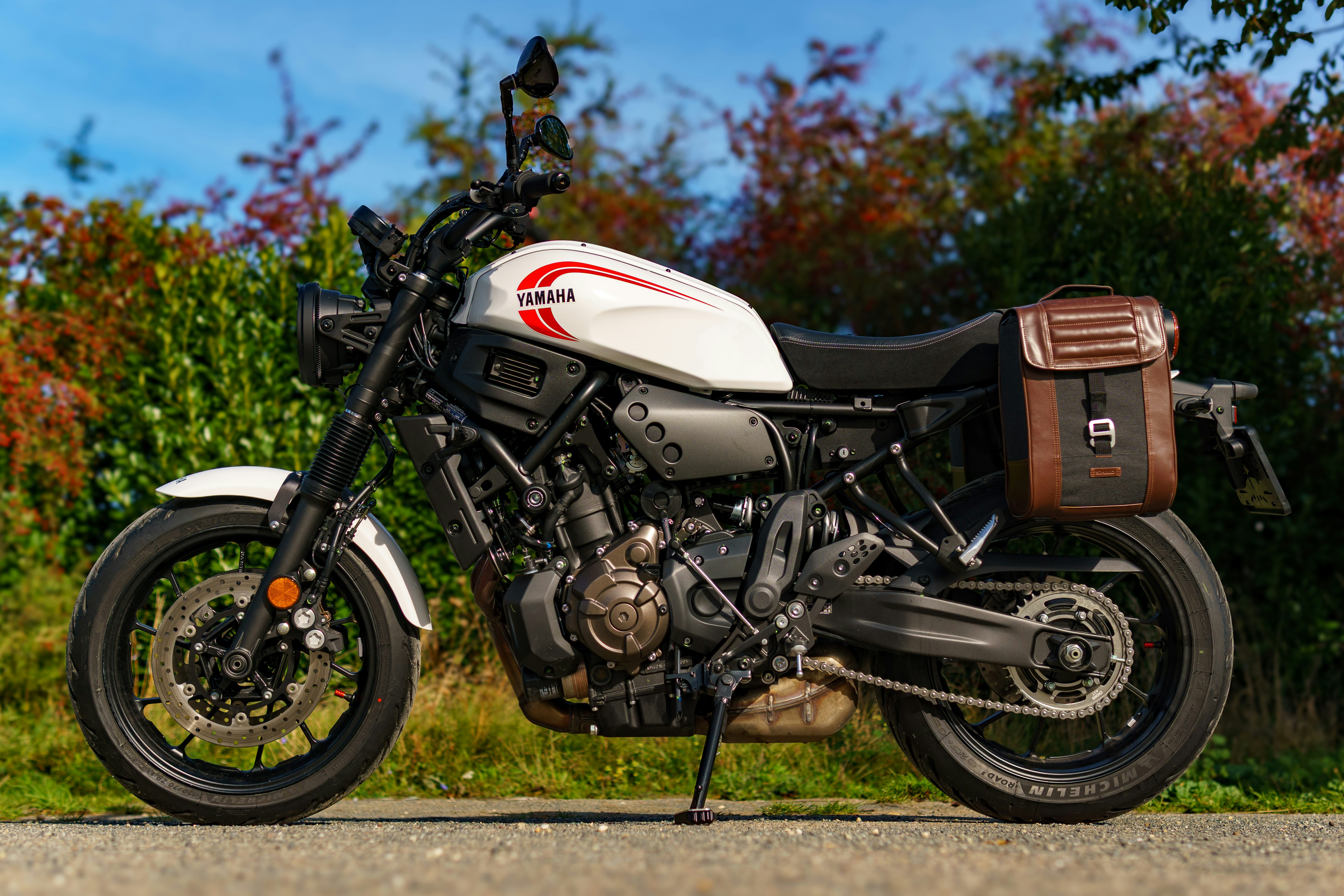 White yamaha motorcycle with brown saddlebag parked outdoors.
