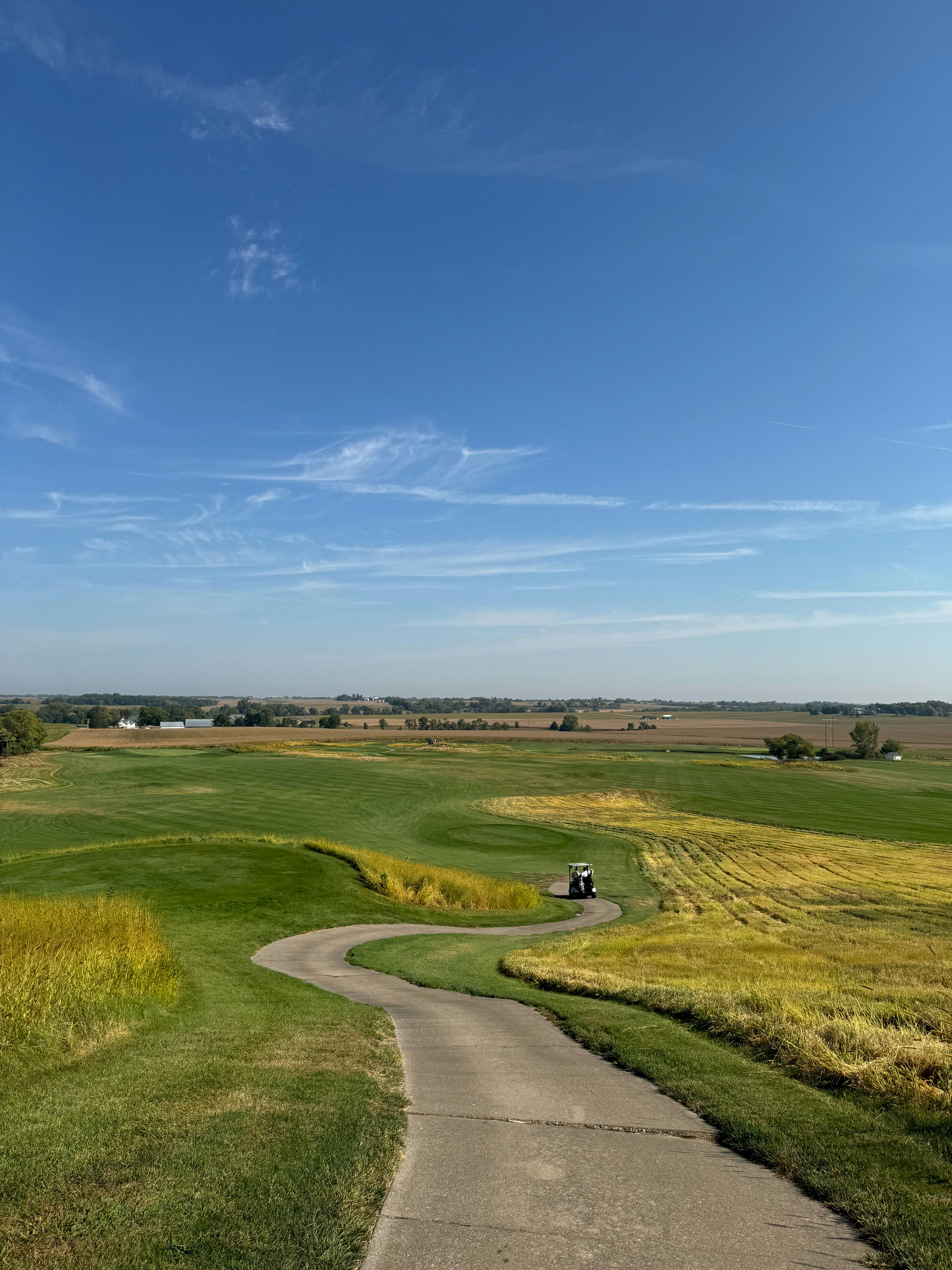 Golf cart on a winding path through lush green fairways