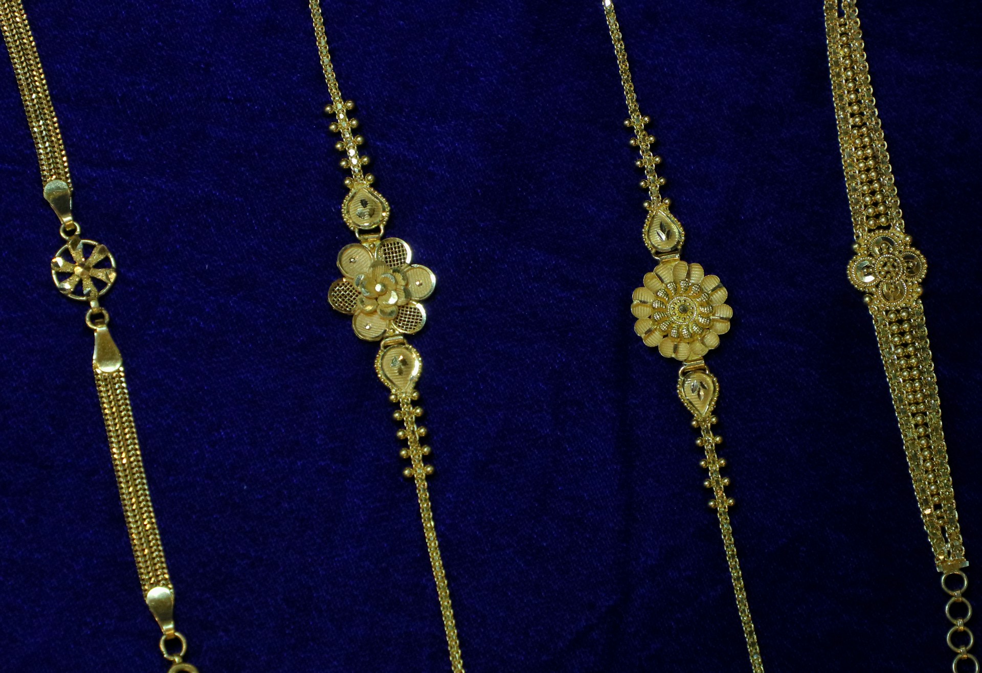 Four delicate gold bracelets on blue velvet