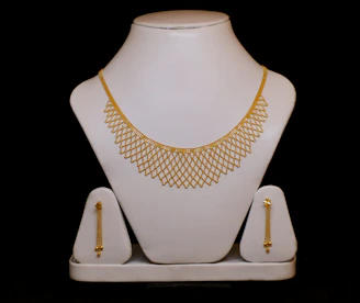 Gold necklace and matching earrings on display.