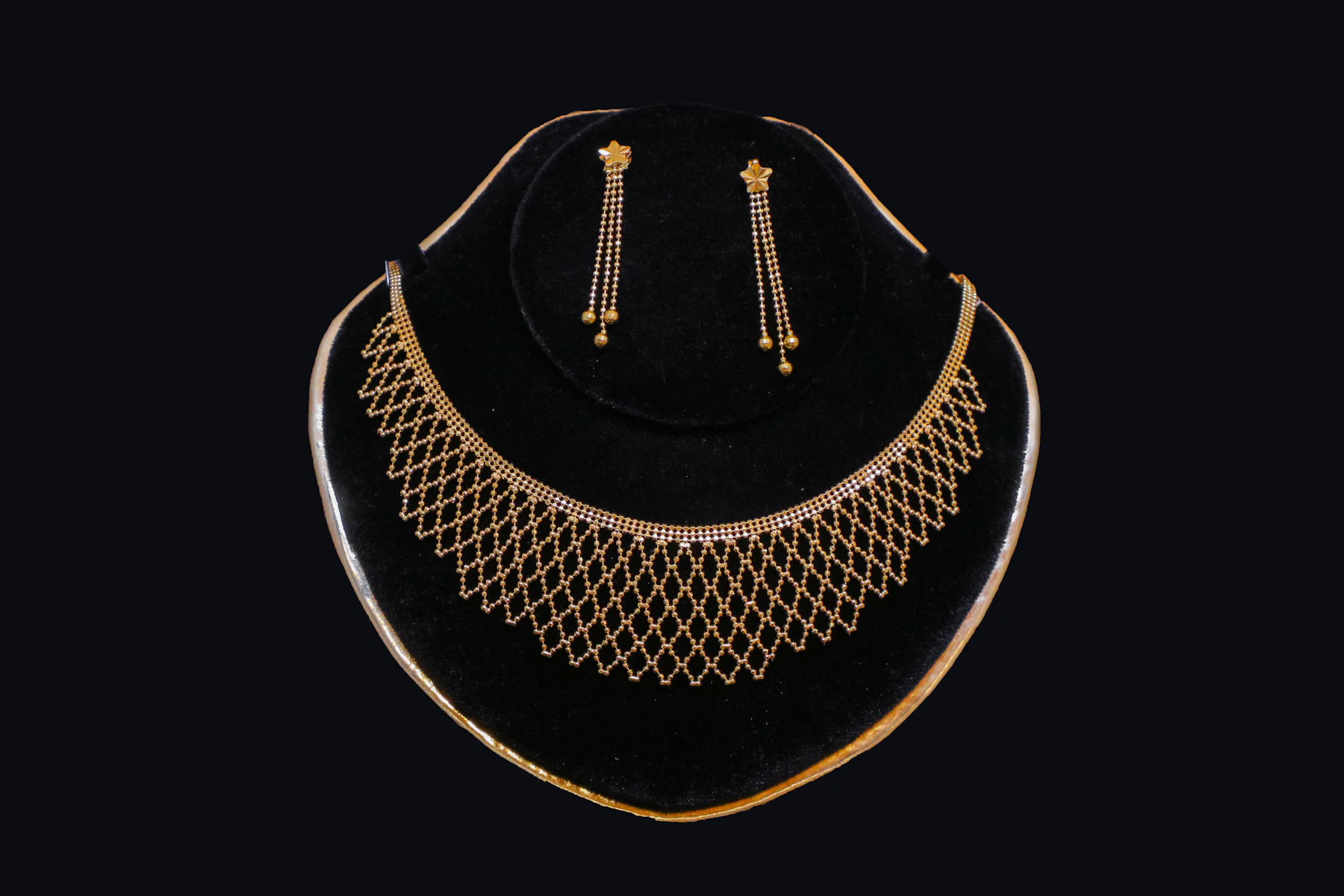 Gold necklace and earrings on black velvet