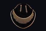 Gold necklace and earrings displayed on black velvet.
