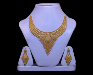 Gold necklace and earrings displayed on white stands.