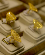Several ornate gold rings displayed on stands