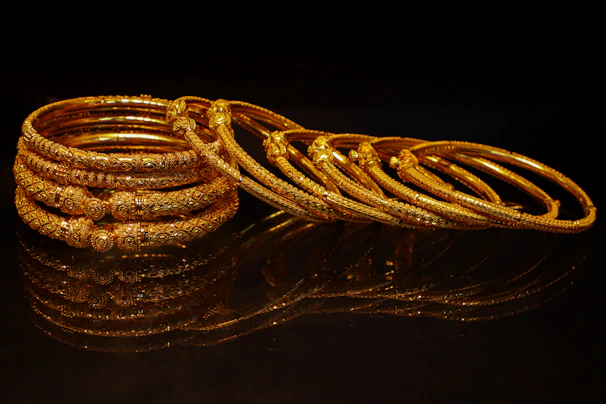 A stack of ornate gold bangles on a dark surface.