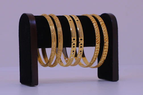 Several gold bangles displayed on a stand.