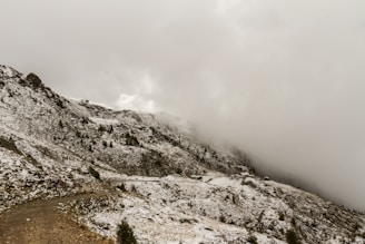 Snow-covered mountain in Mallorca slope with clouds obscuring the peak.