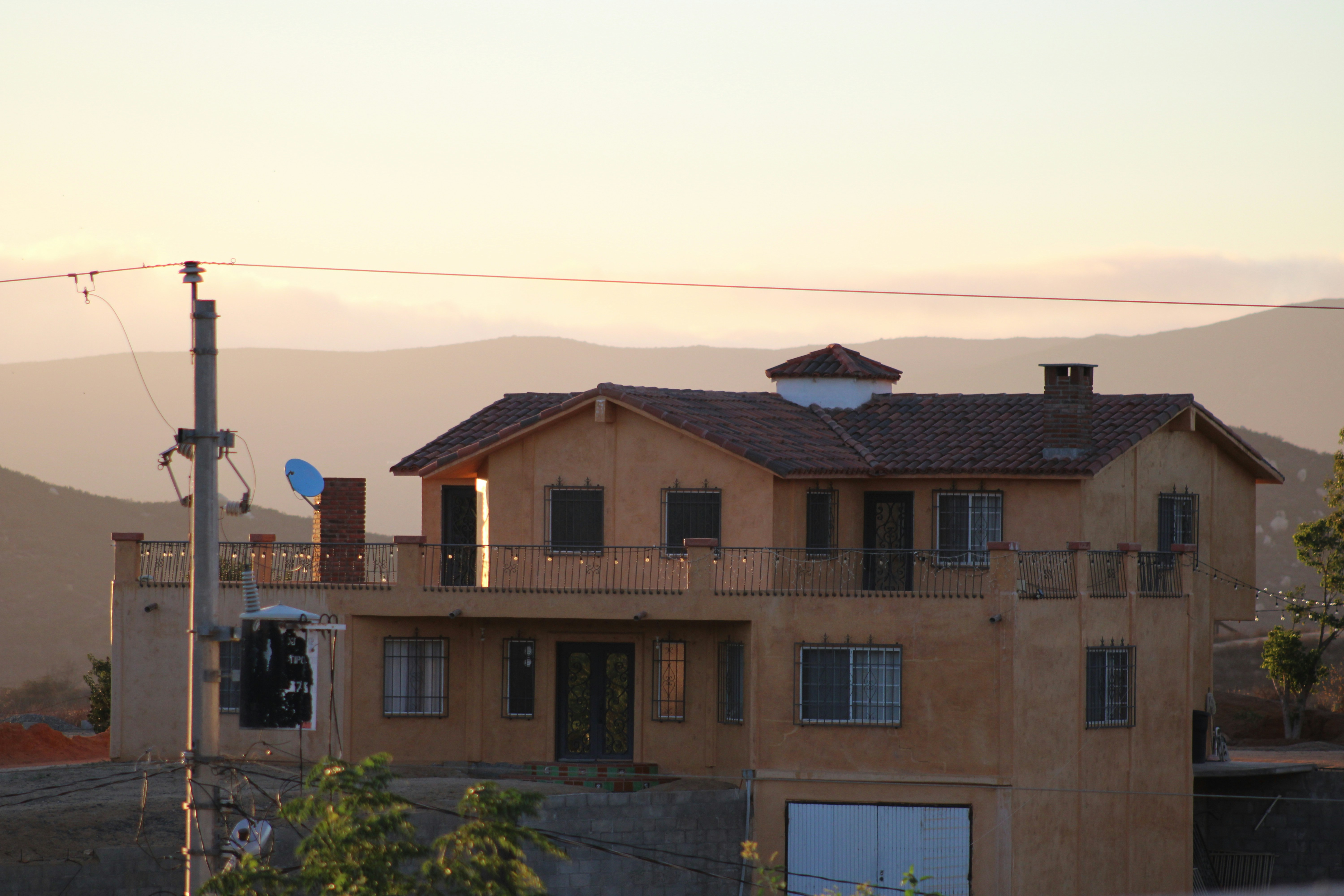 A large house with a balcony at sunset.