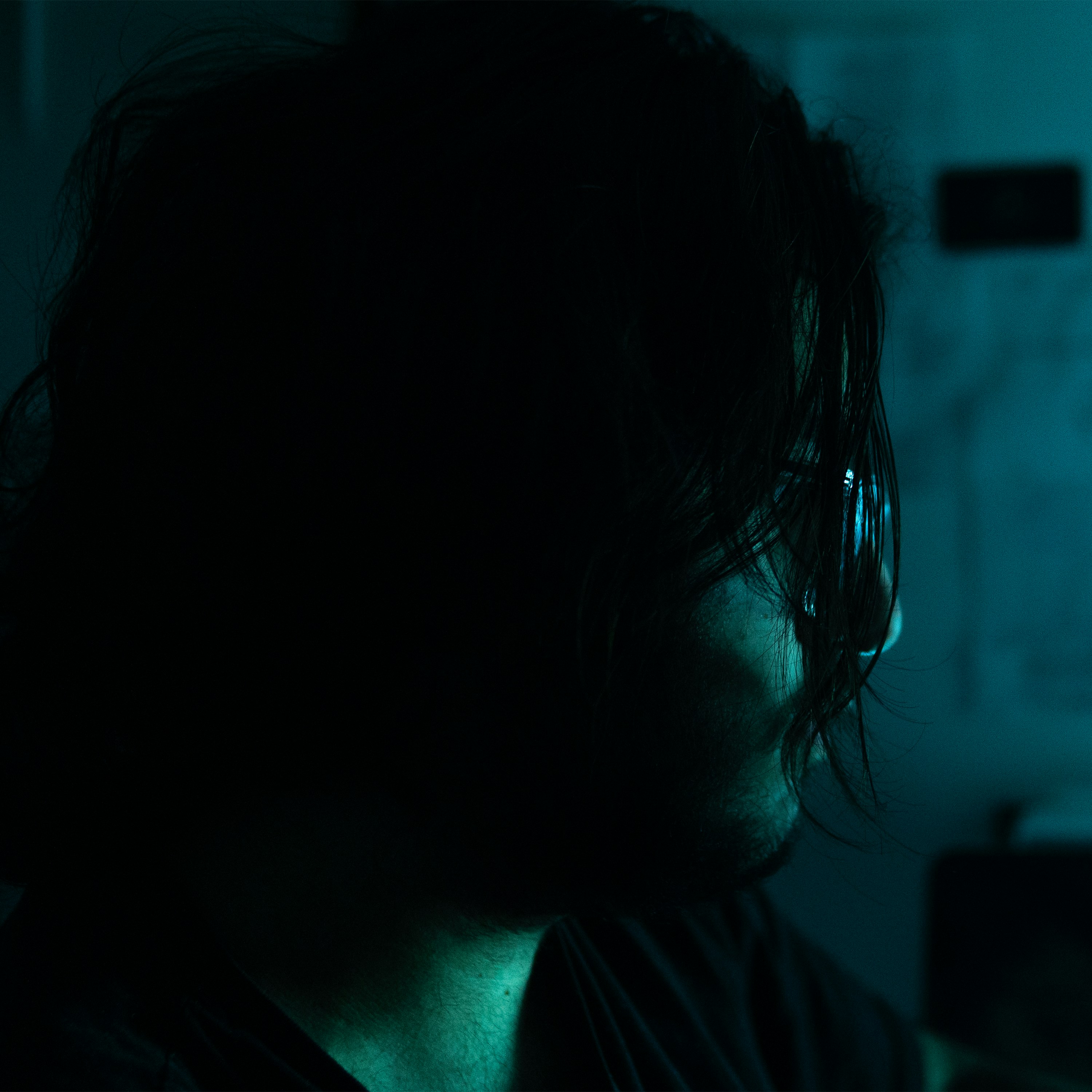 Person with dark hair in dim blue light