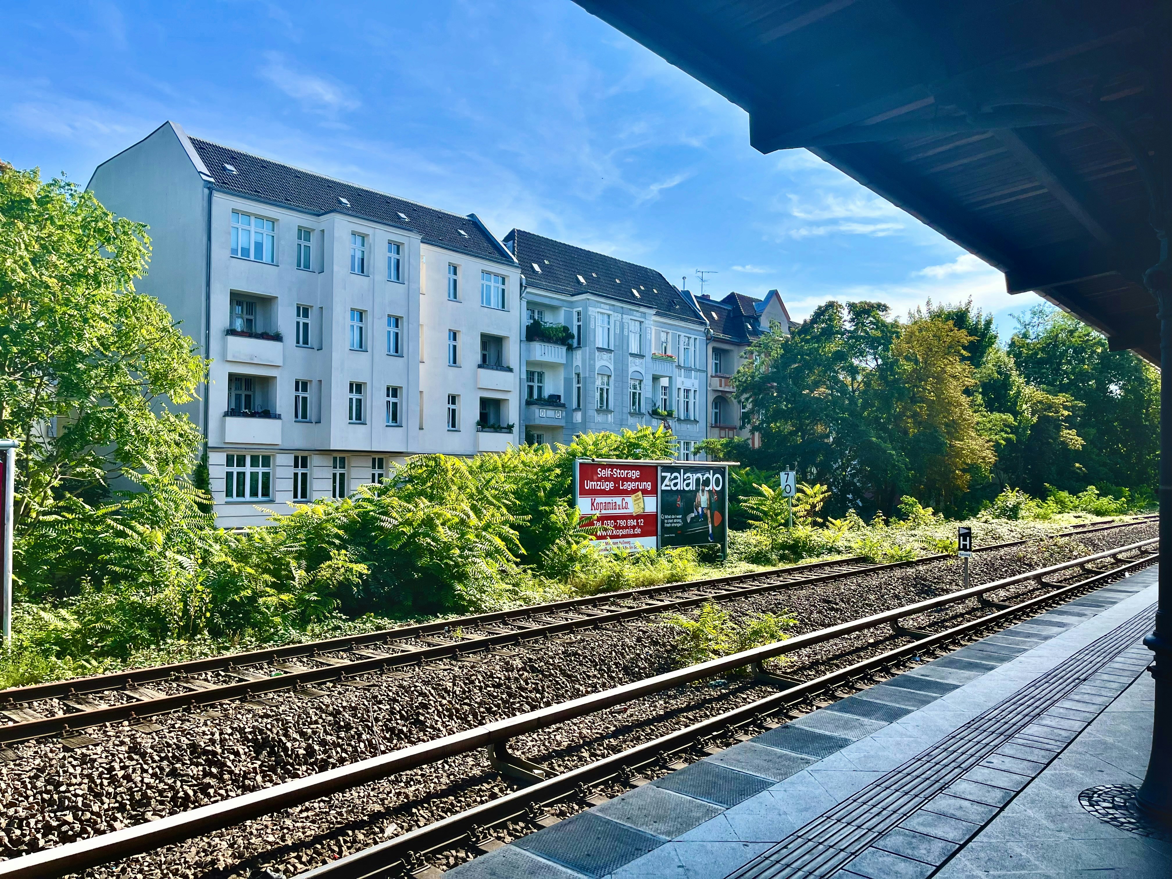 Apartment buildings beside train tracks under a blue sky.