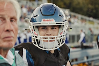 Young football player in helmet with coach watching