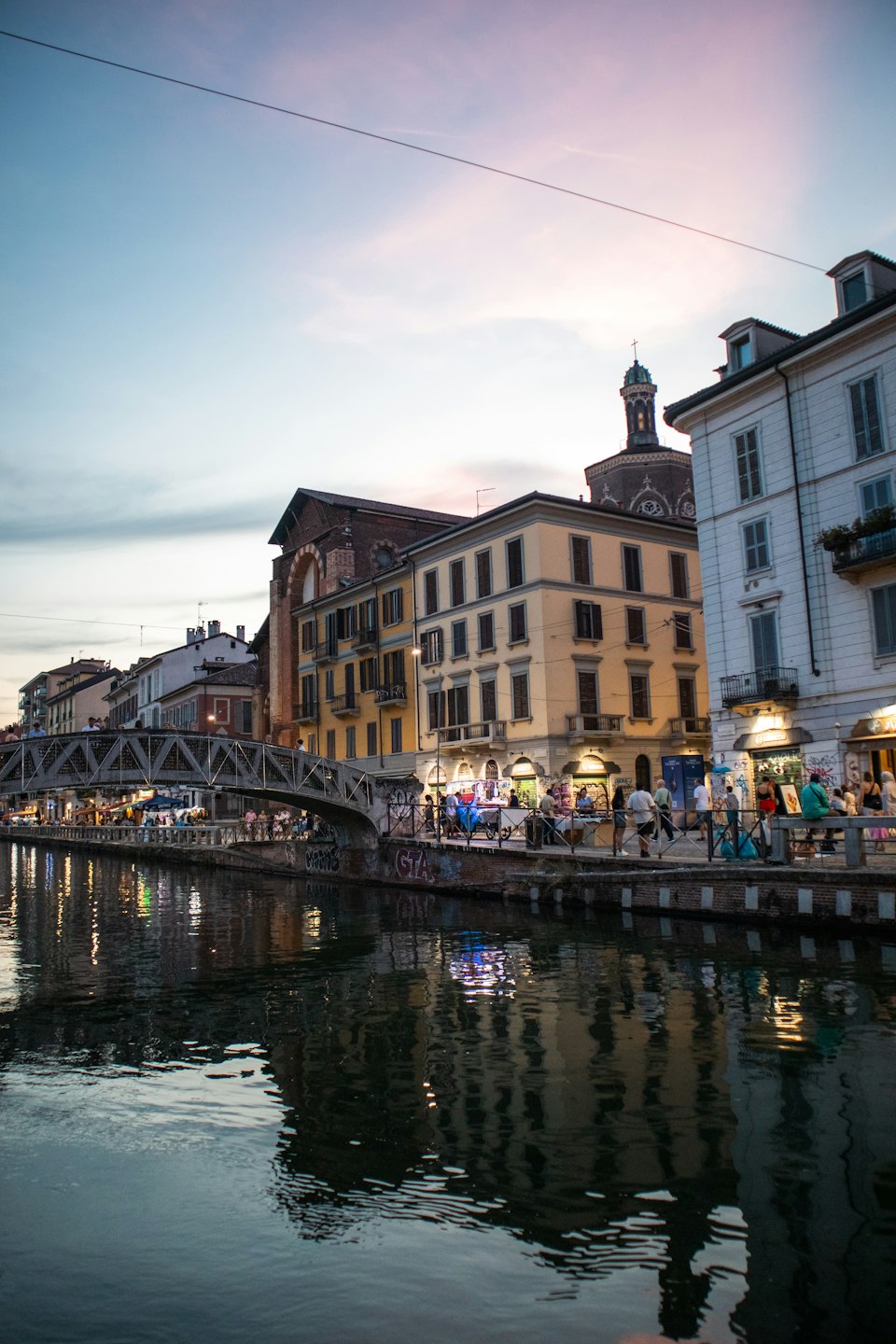 A Navigli canal bridge and buildings lit up at dusk