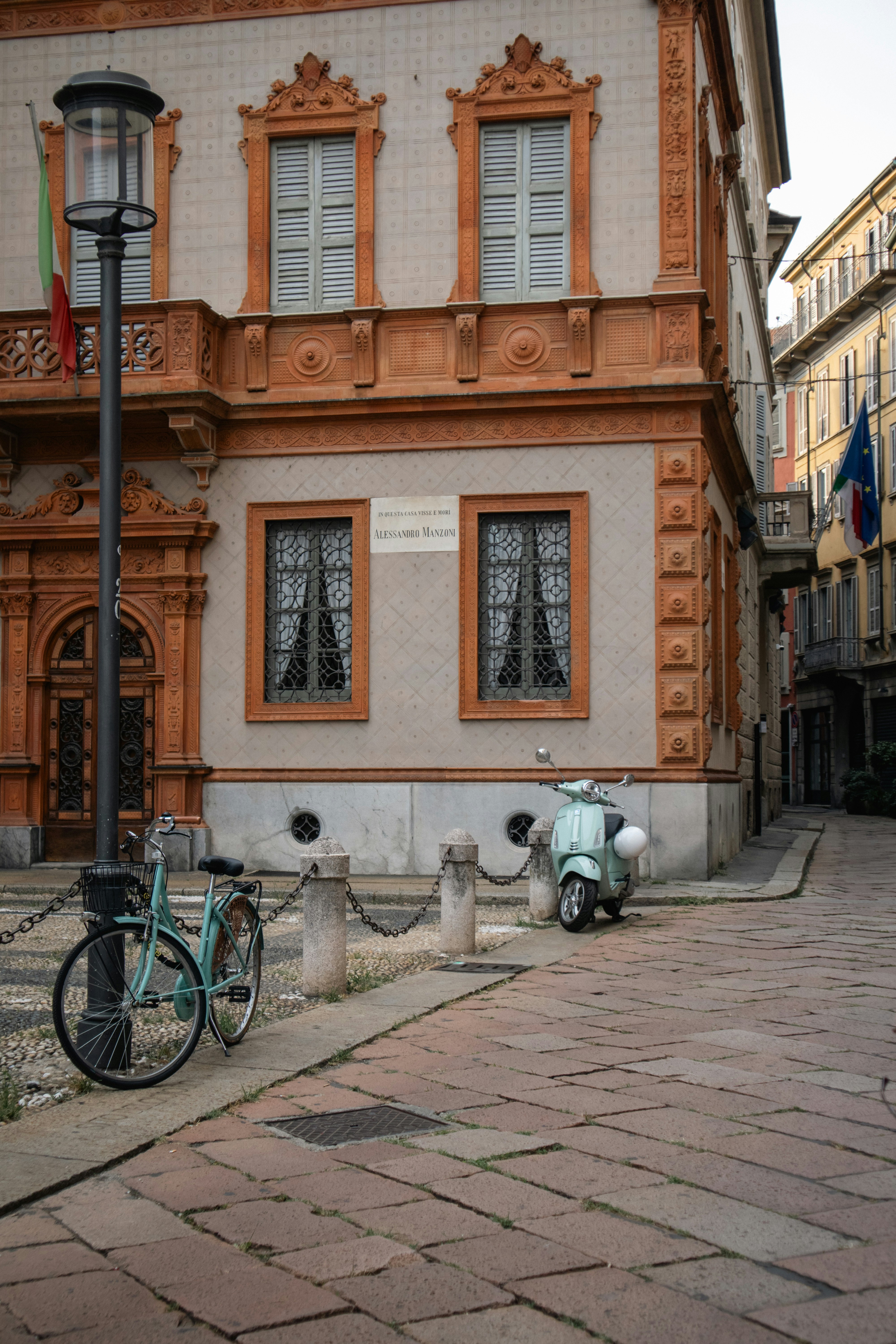 Vintage bicycle and scooter parked on cobblestone street.