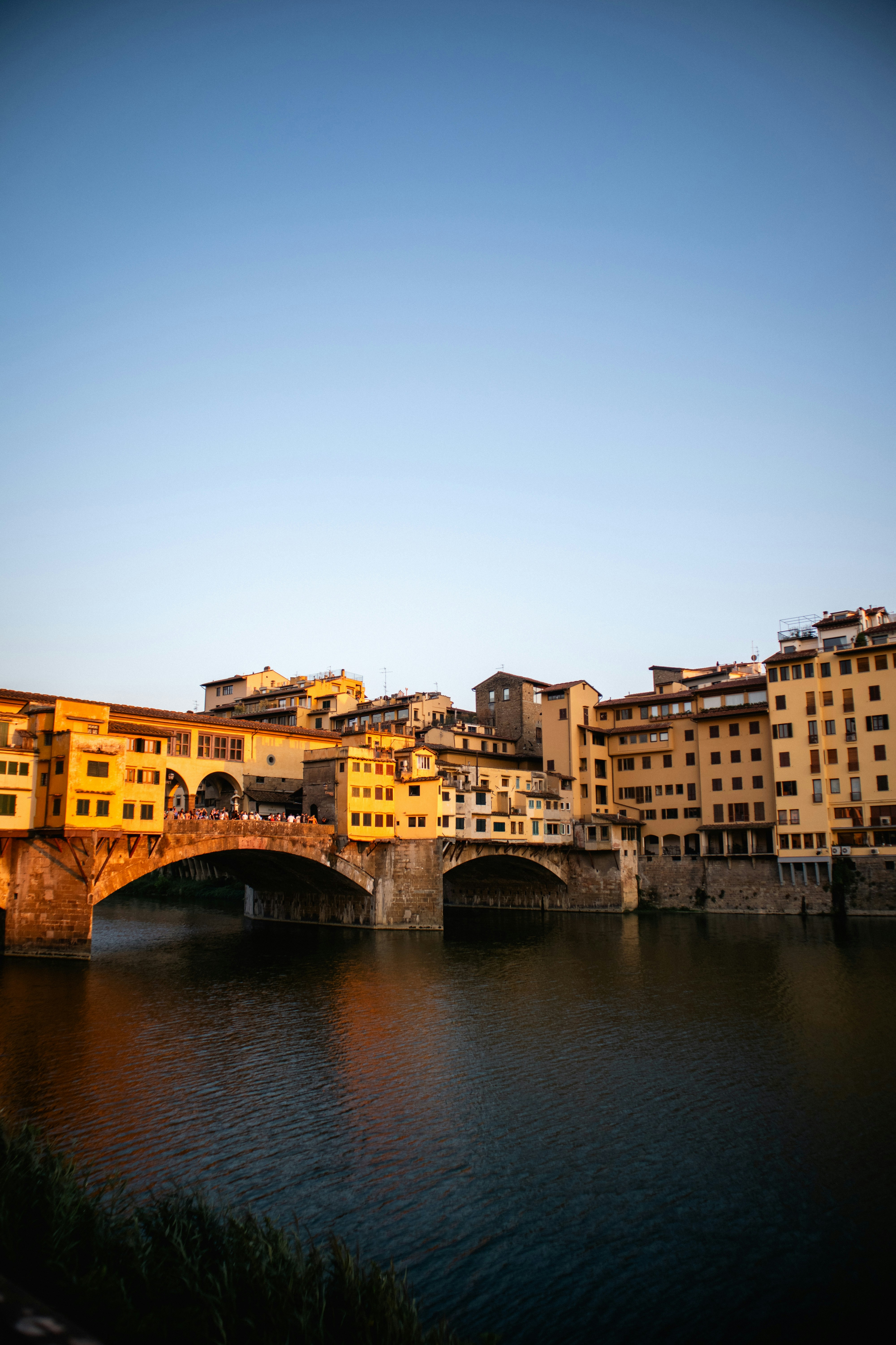 Ponte vecchio bridge at sunset over the arno river.