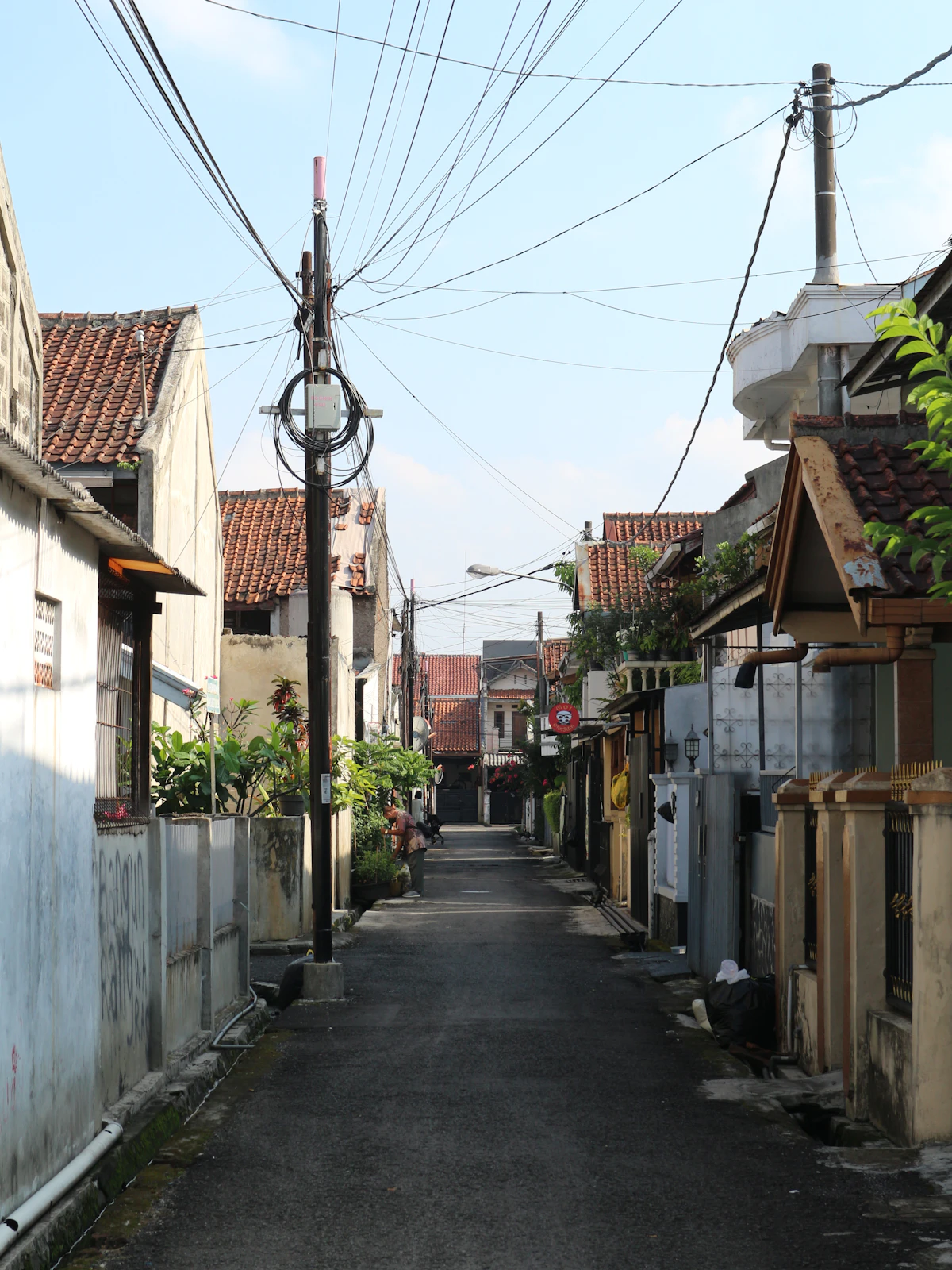 Gang sempit permukiman dengan deretan rumah dan tiang listrik