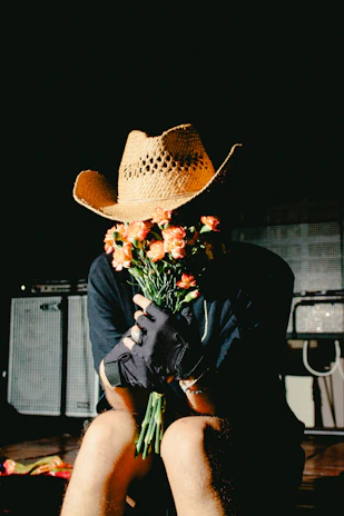 Person in cowboy hat holding orange flowers