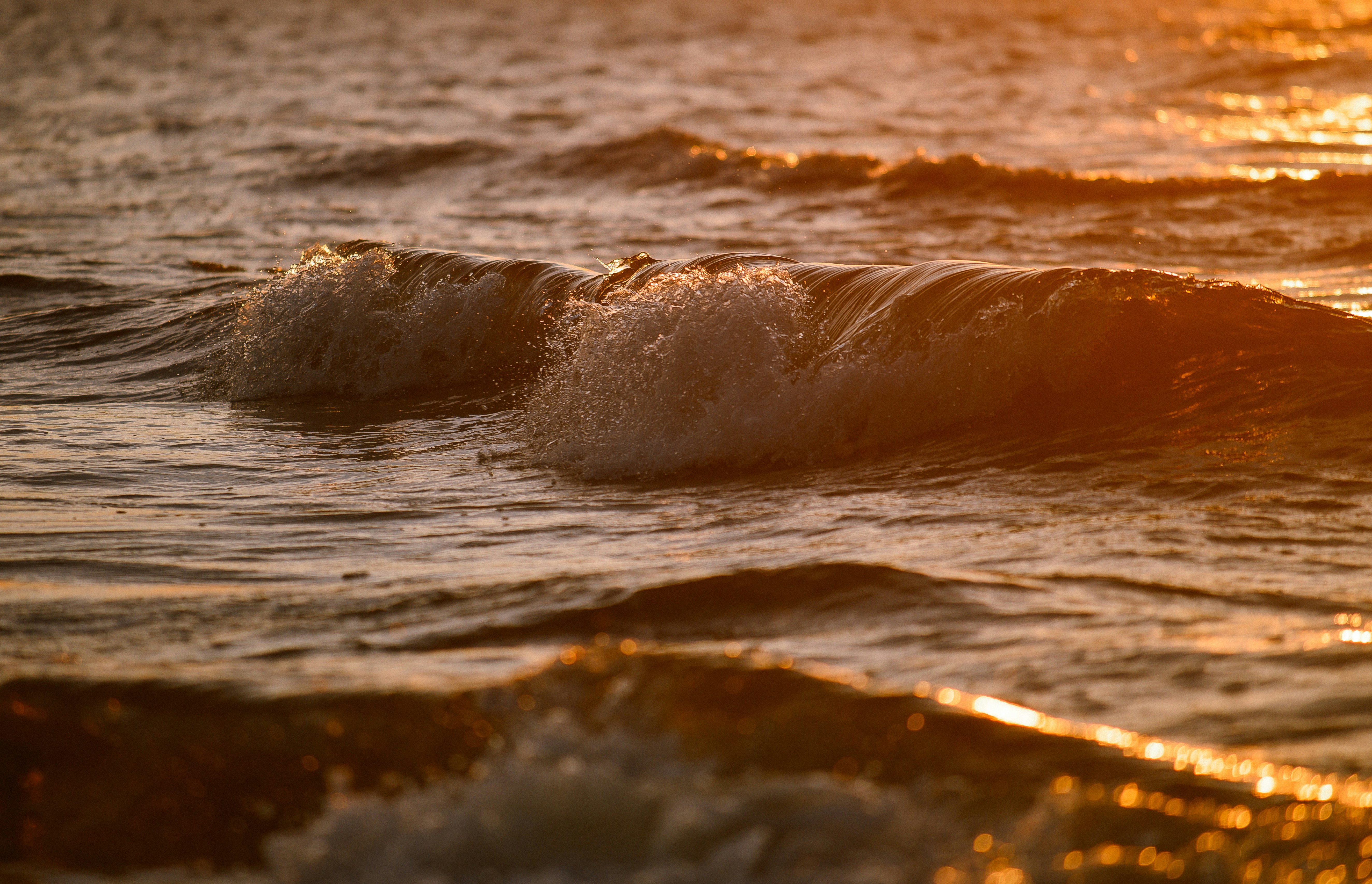 Gentle ocean waves at sunset with golden light.