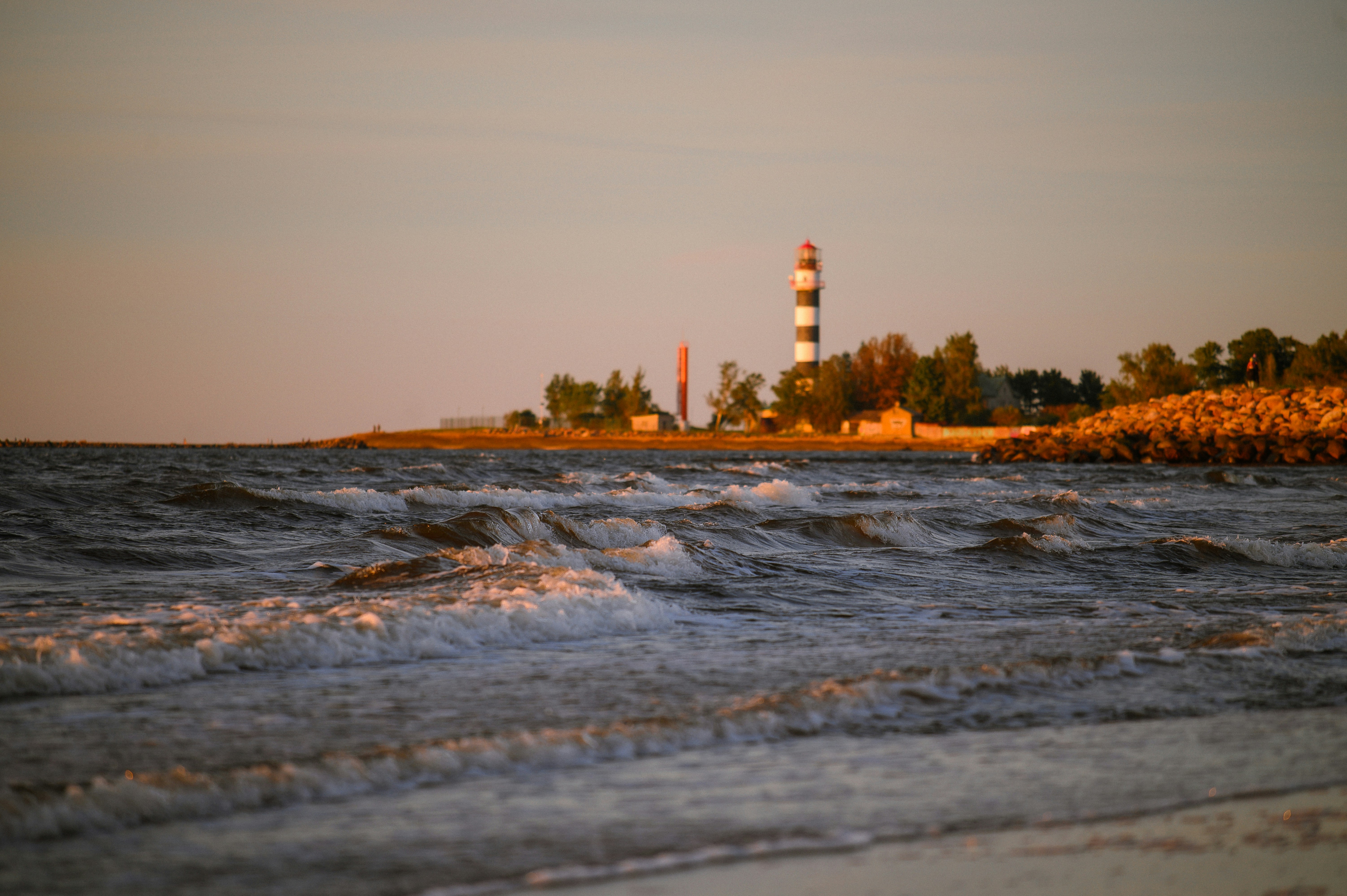 Lighthouse on a rocky shore at sunset