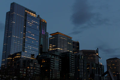 Modern skyscrapers illuminated at dusk with cloudy sky.