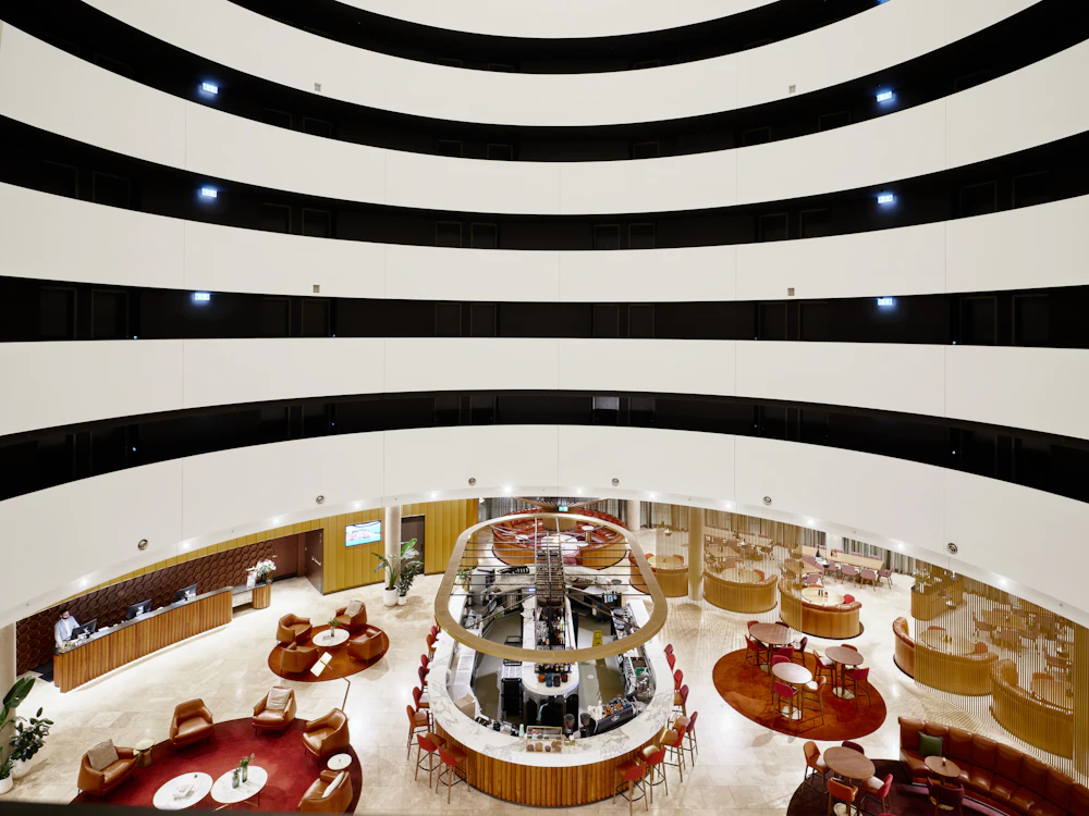 An interior with circular seating beneath an atrium
