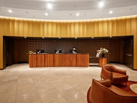 Hotel reception desk with modern wooden furniture and seating.