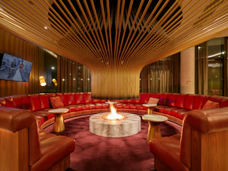 Circular lounge with a central fireplace and red sofas.