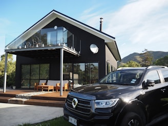 Modern black house with a car parked outside.