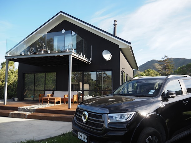 Modern black house with a car parked outside.