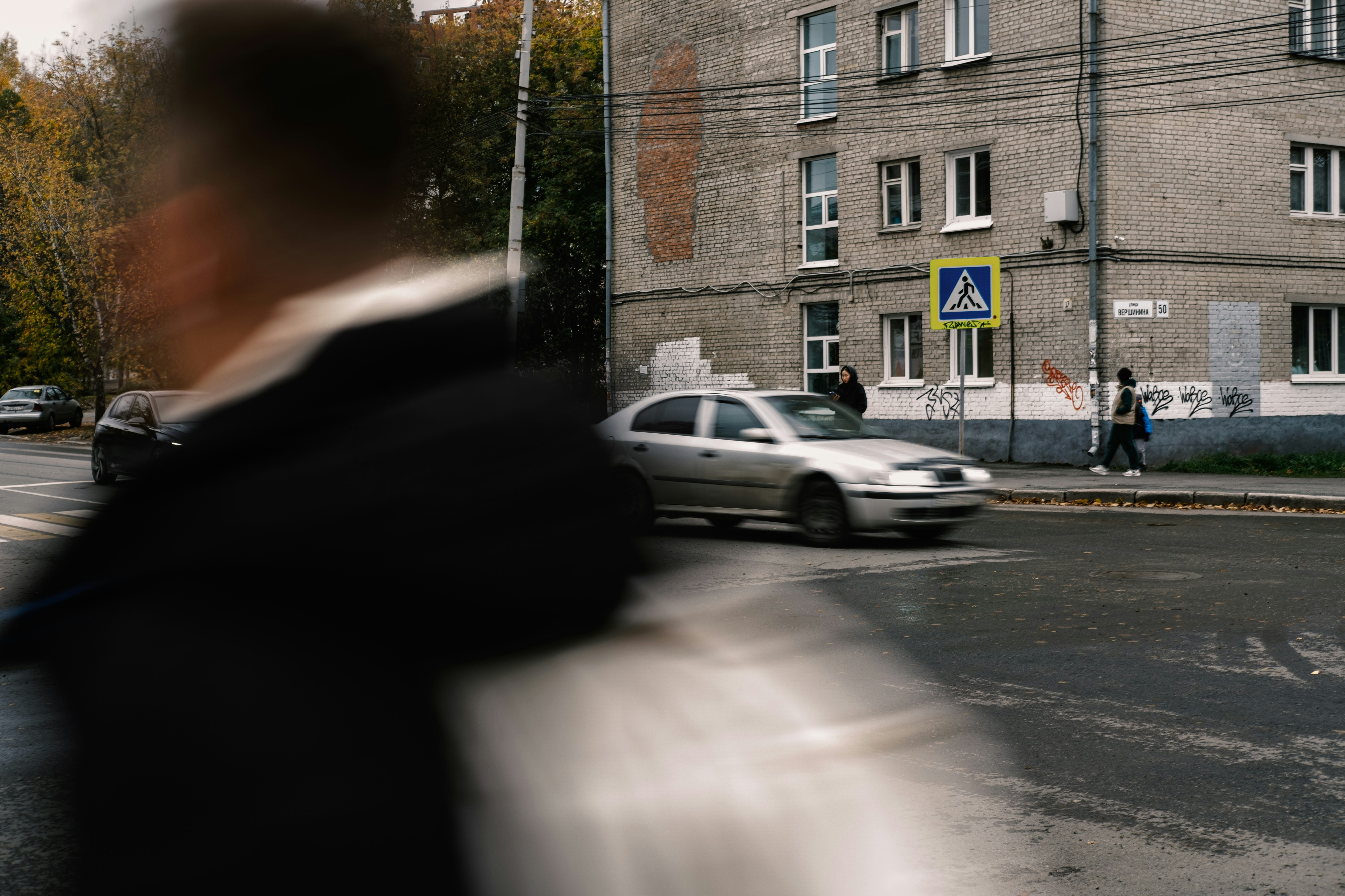 A police officer in uniform apprehending a person, possibly in a residential area, with a generic background. The person's face is obscured or blurred.