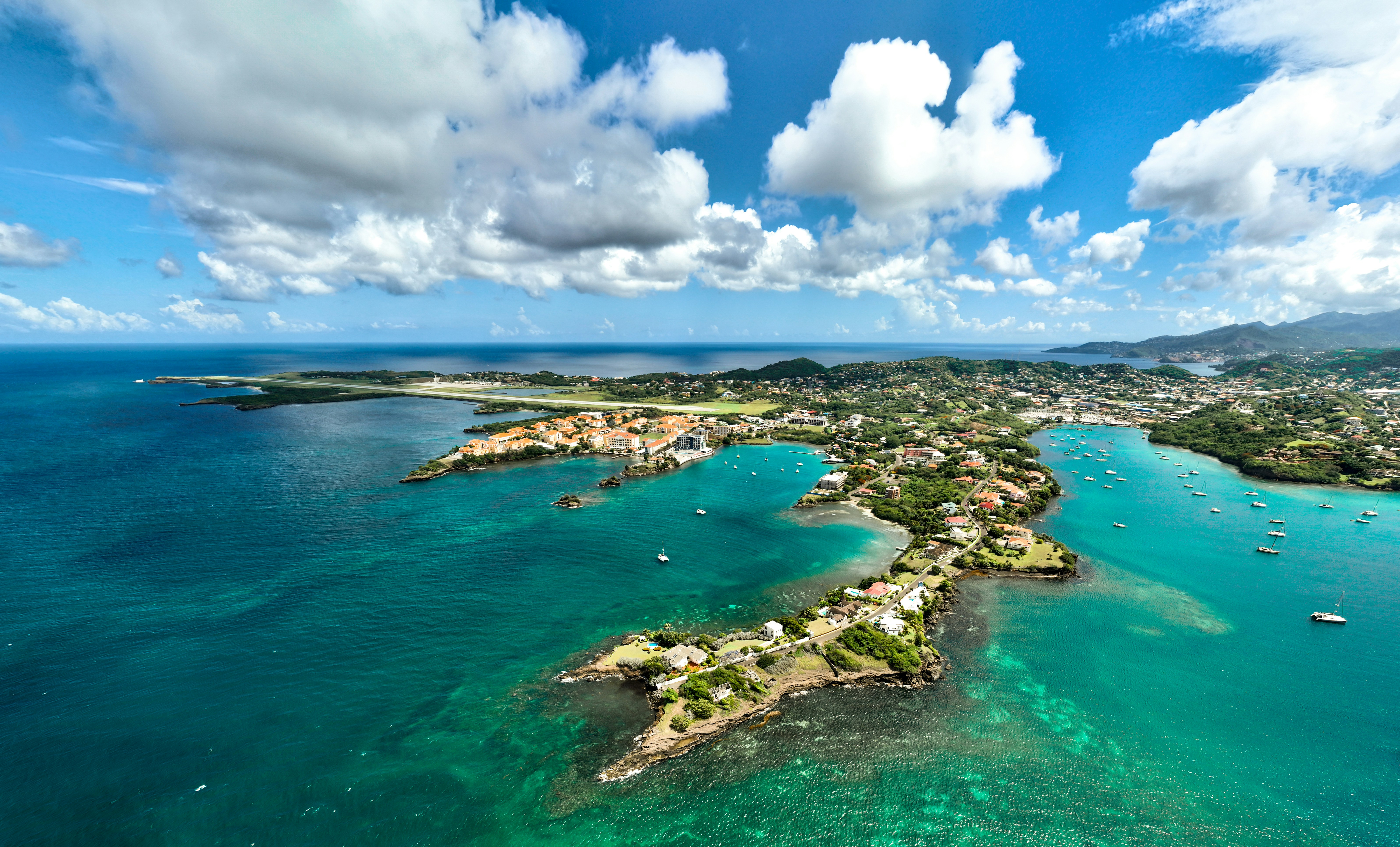 青空の下、ターコイズブルーの湾にボートが停泊する海岸沿いの町