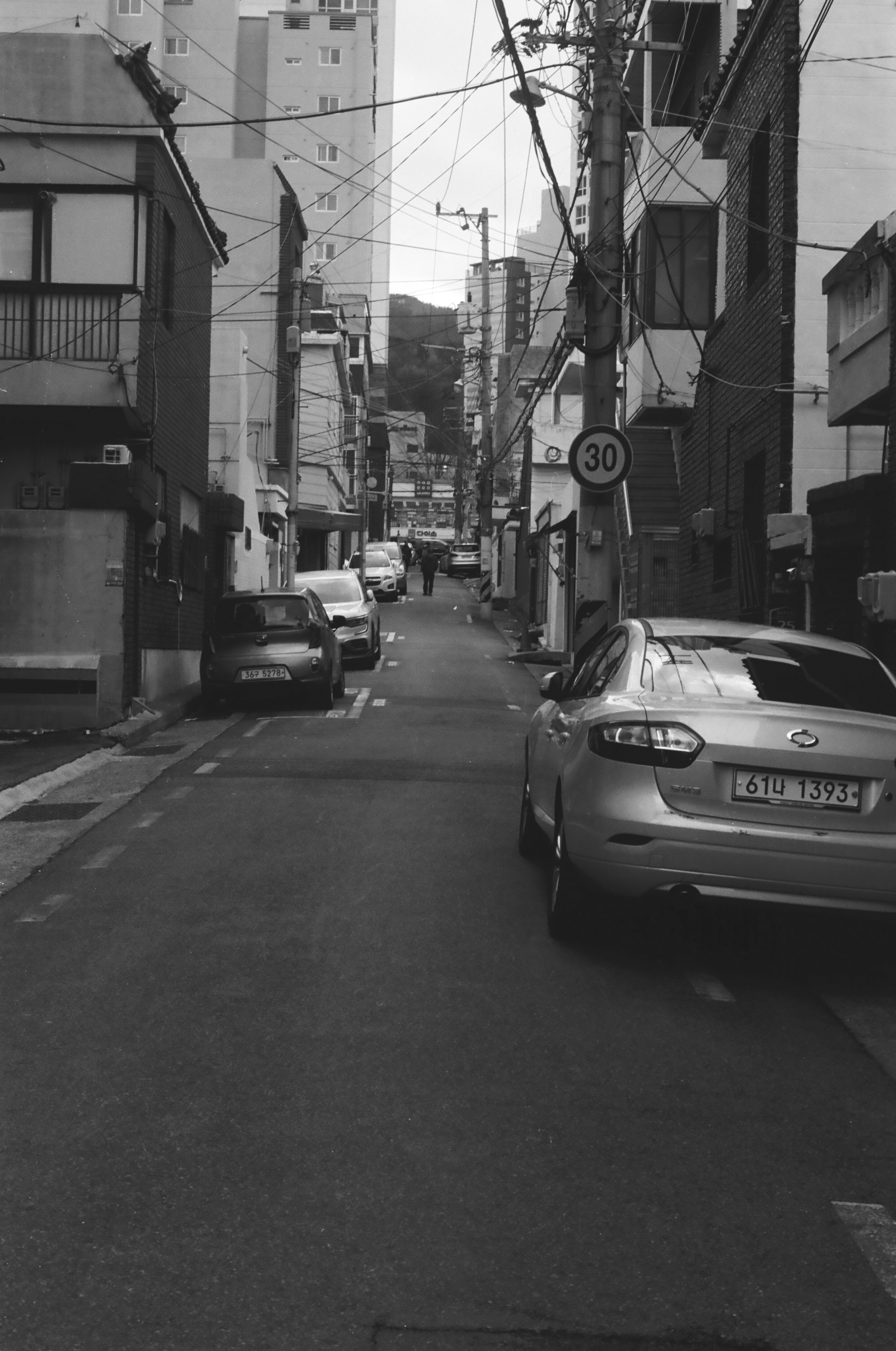 Cars parked on a narrow city street with buildings.