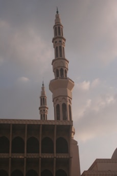 Two mosque minarets against a cloudy sky