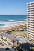 High-rise building overlooking a beach and tennis courts.