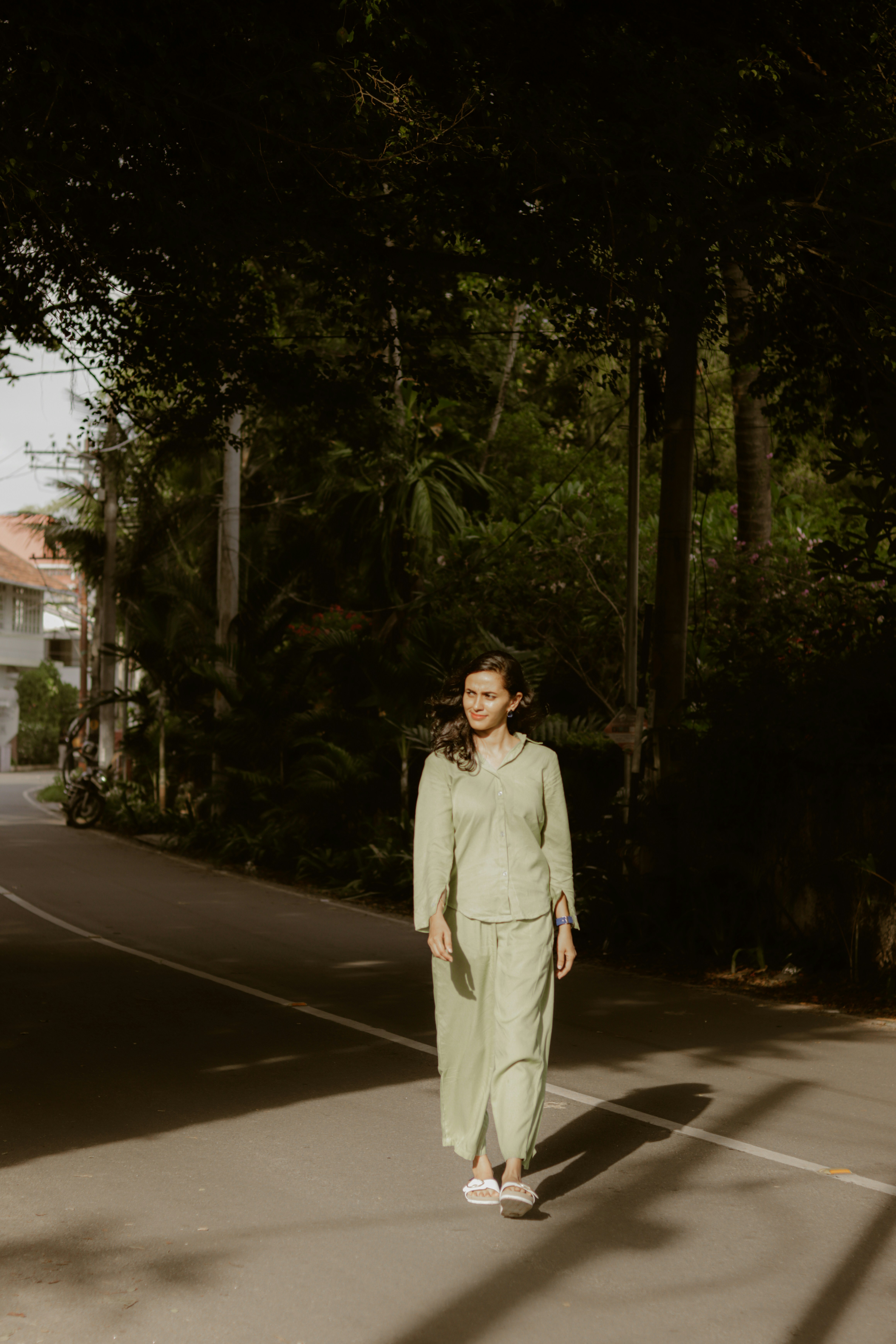Woman in a light green tracksuit walking on a road.