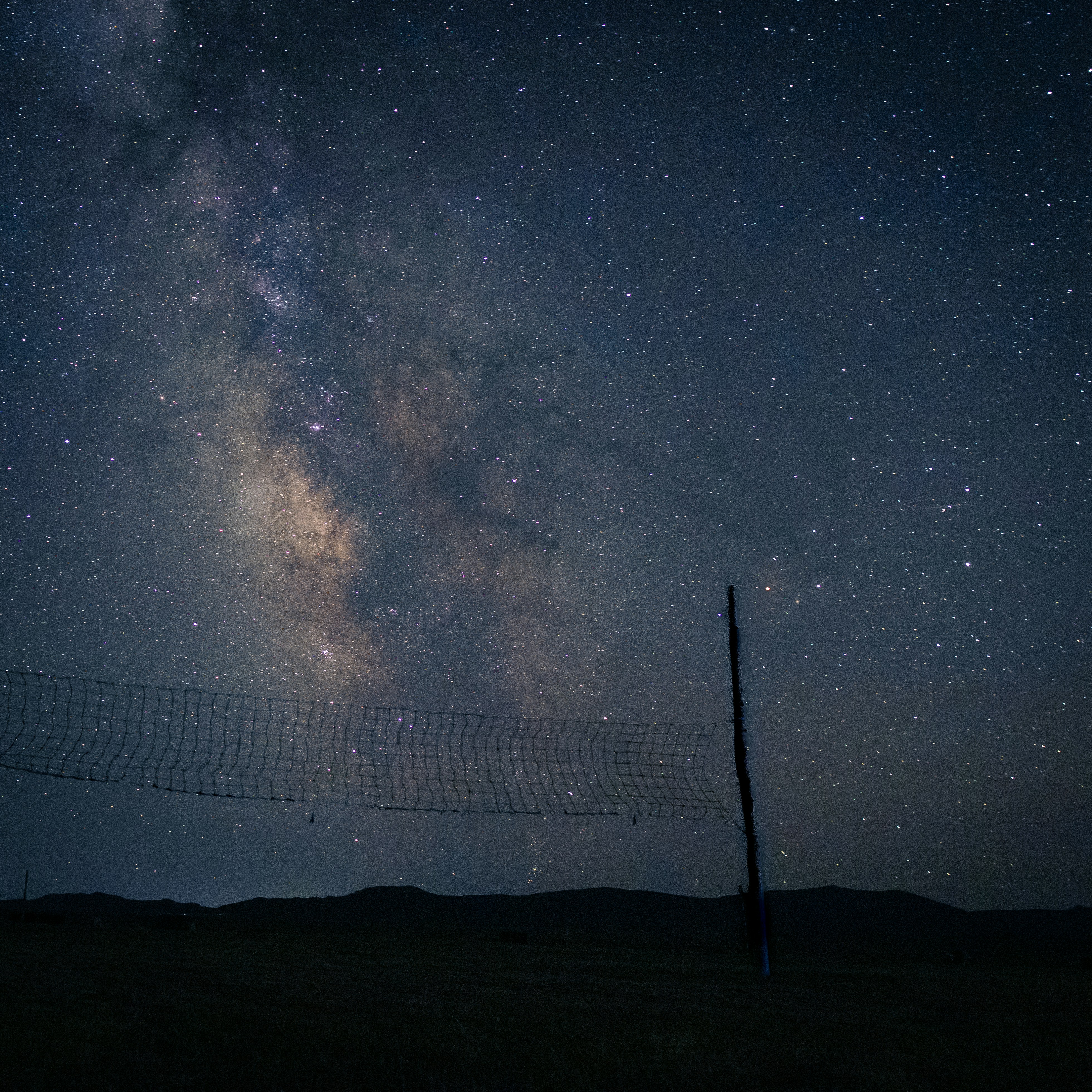 Milky way galaxy over a dark landscape with pole.