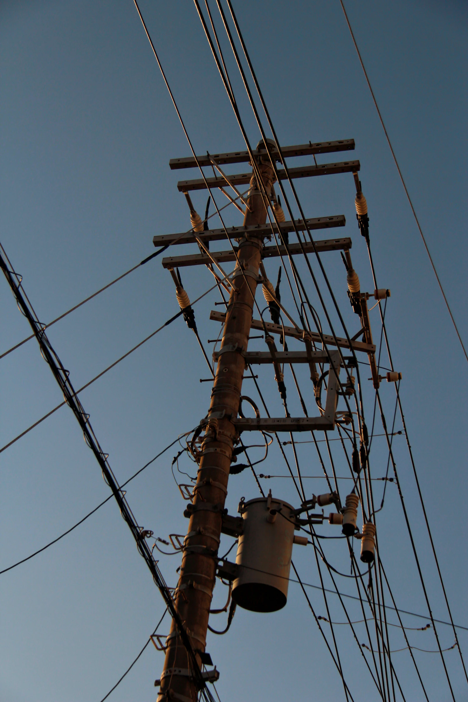変圧器の付いた木の電柱と、空に張られた電線