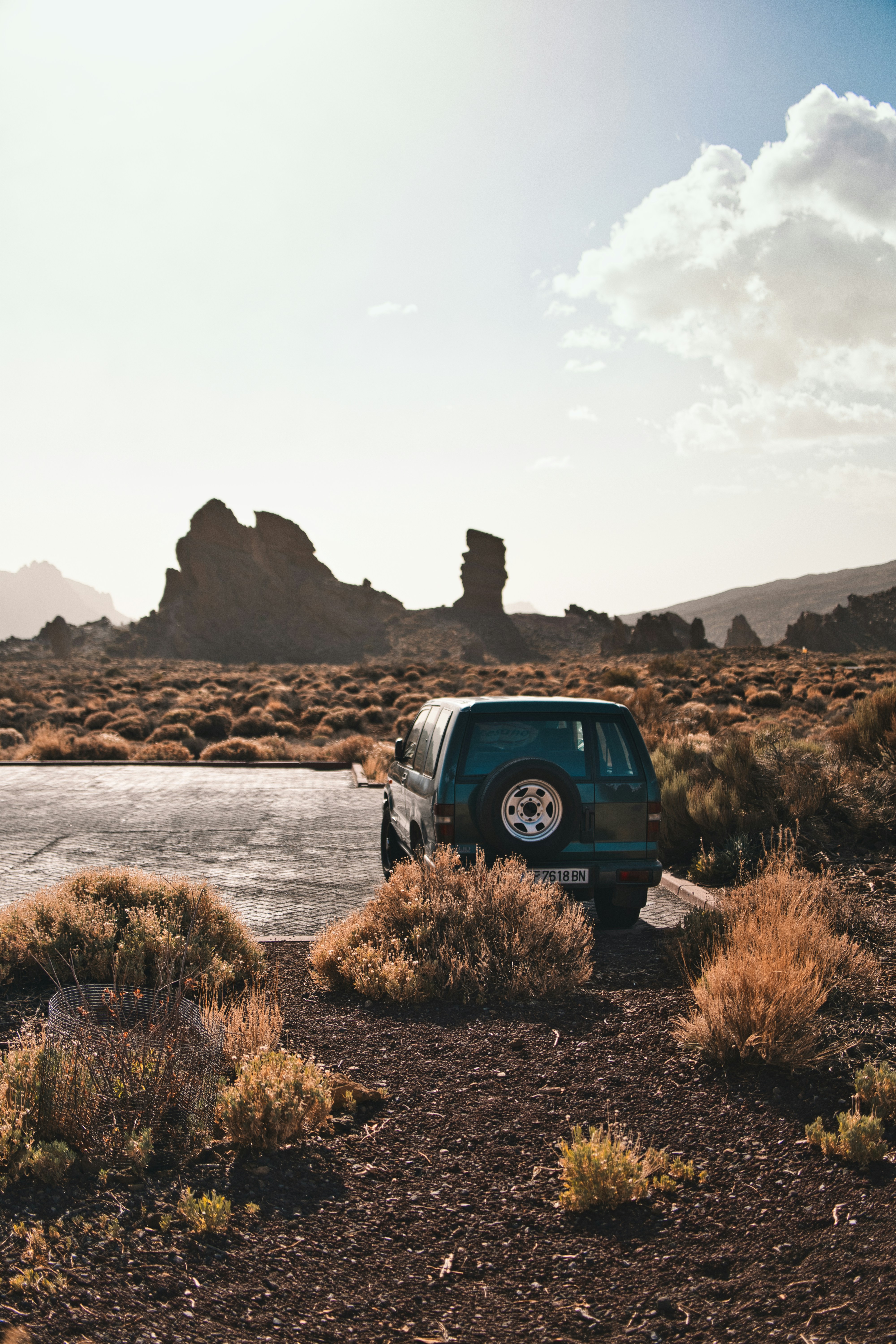 A dark green suv parked on a rocky, arid landscape.