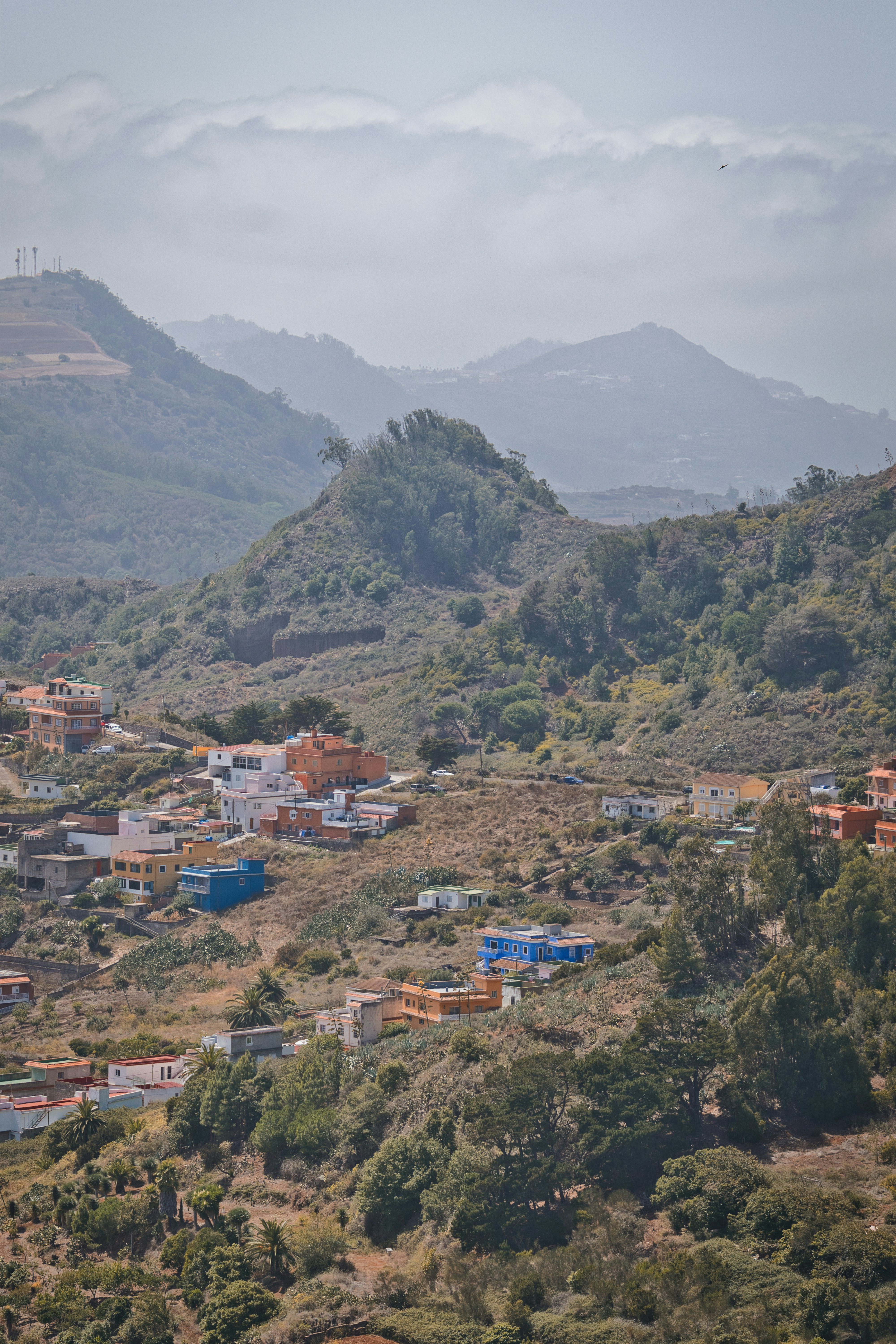 Colorful houses nestled on a green, hilly landscape.