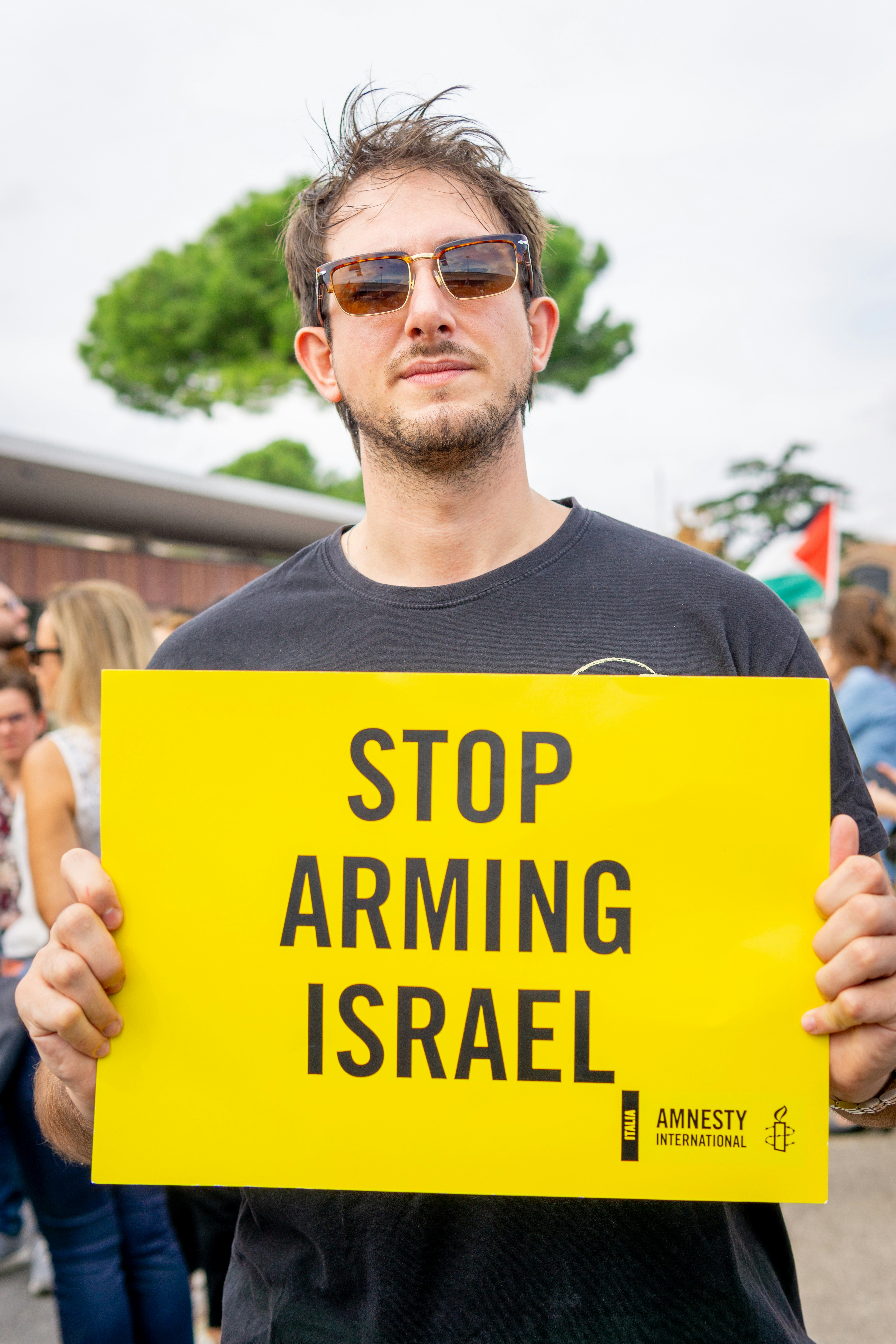 Man holds yellow sign saying stop arming israel