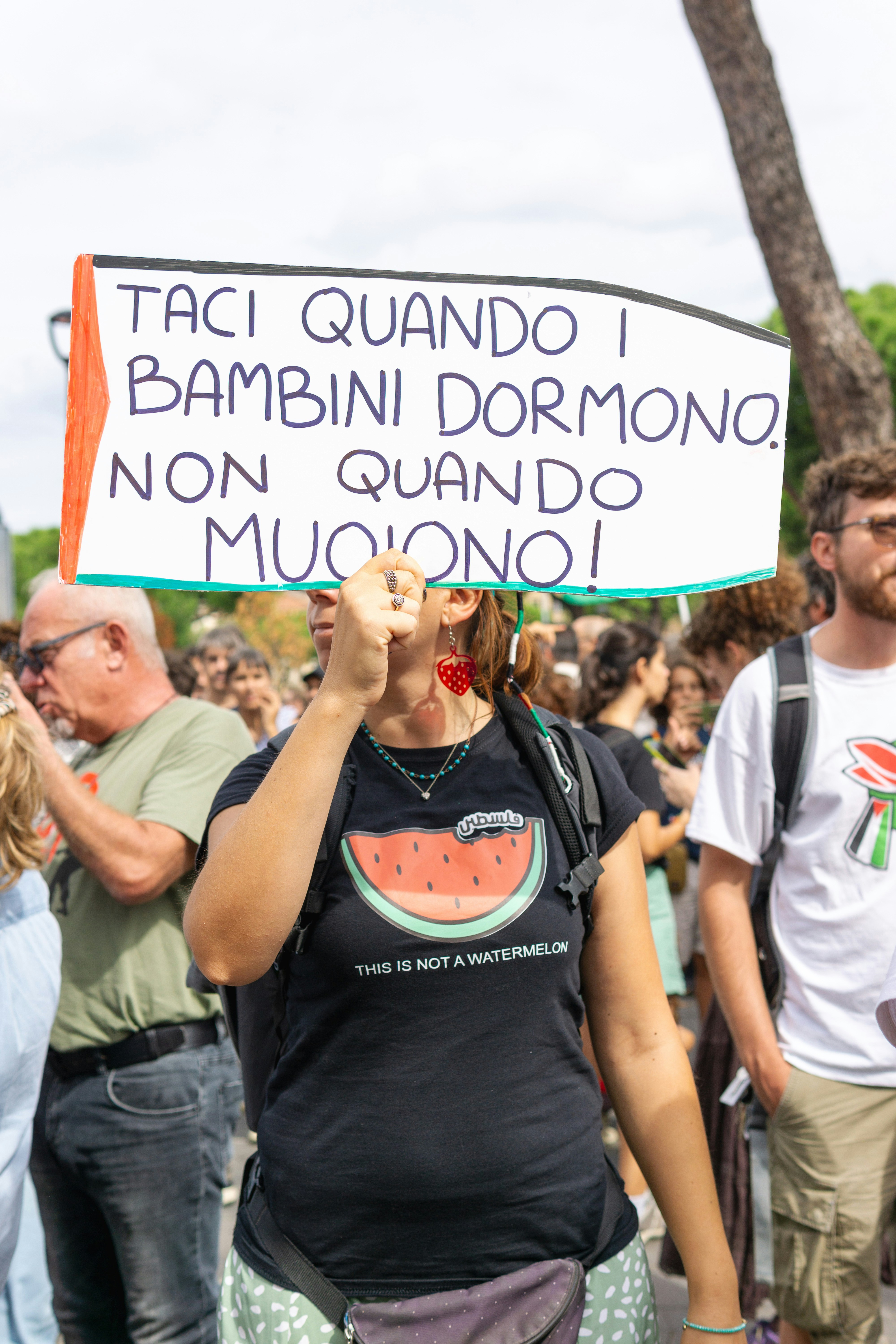Woman holds sign at protest with text in italian.